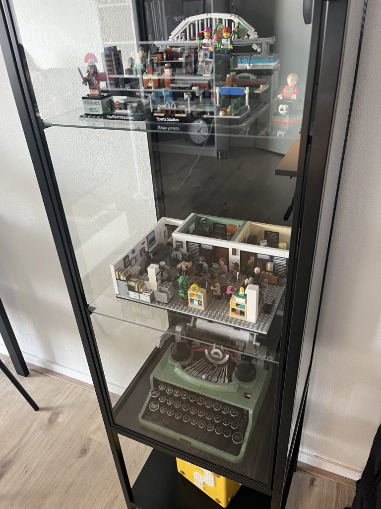 Vitrinekast met LEGO. Van boven naar beneden: Nijmegen-LEGO, set van de comedyserie The Office (US), Typemachine en het vraagtekenblok uit de Mario-reeks.